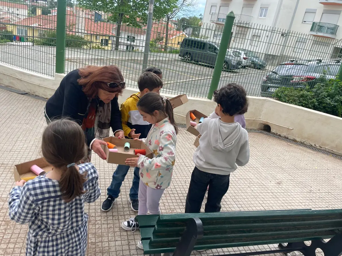 Une senior aide un enfant à faire tenir une balle en équilibre dans un labyrinthe fait d’une boîte et de rouleaux en carton.